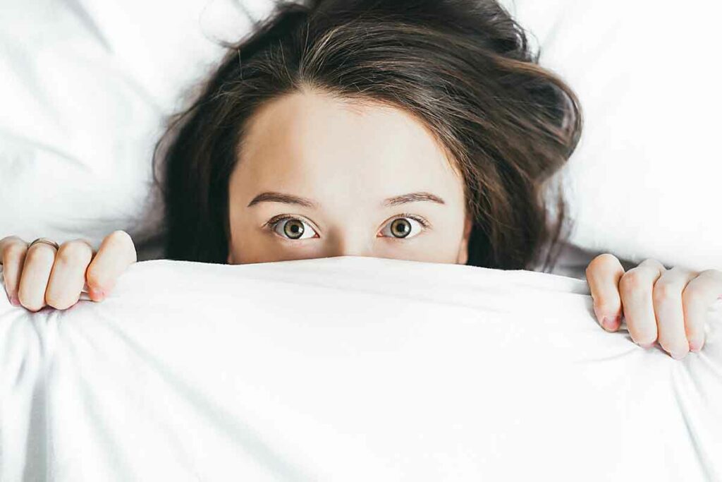 woman hiding under blanket making excuses not to go to rehab