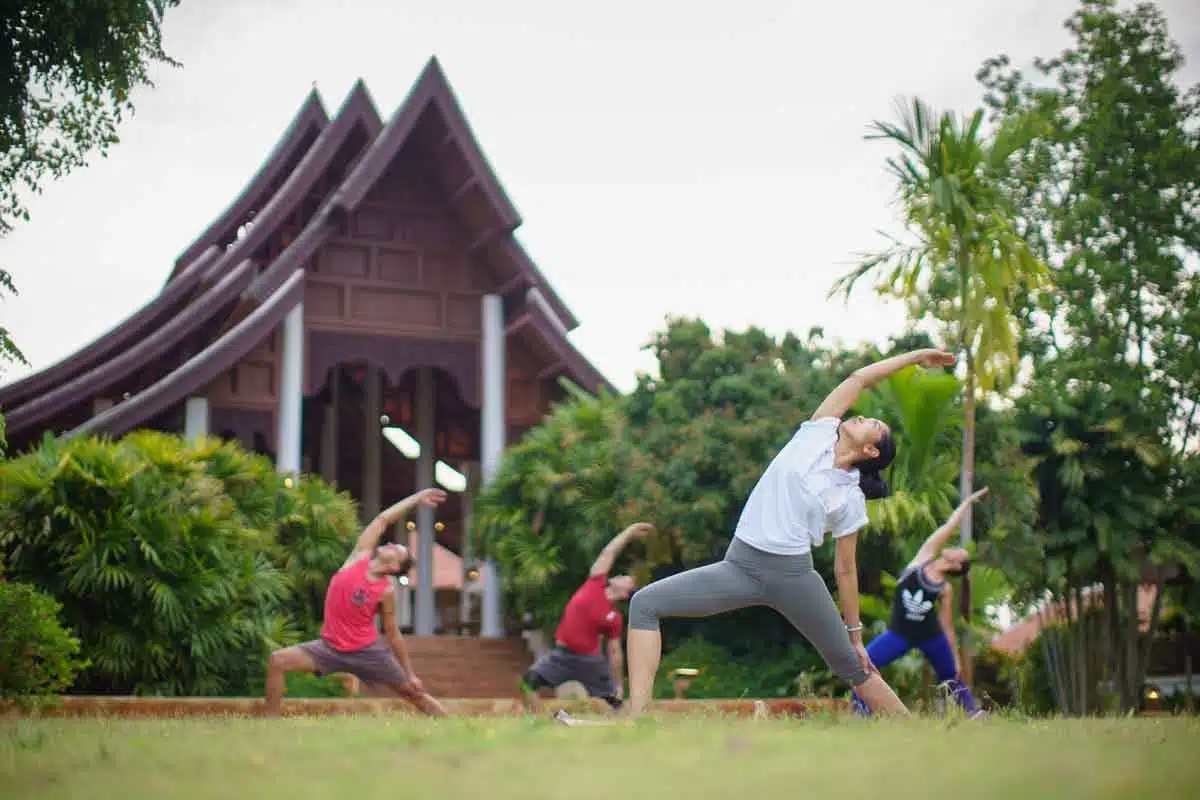 A group of four people doing a standing yoga pose on a lawn at The Dawn.