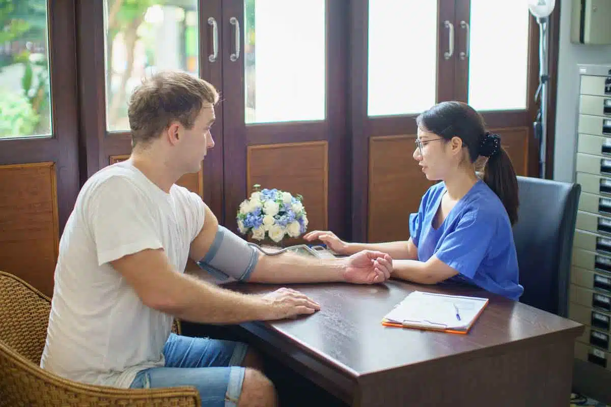A nurse checking a man's blood pressure at a desk at The Dawn.