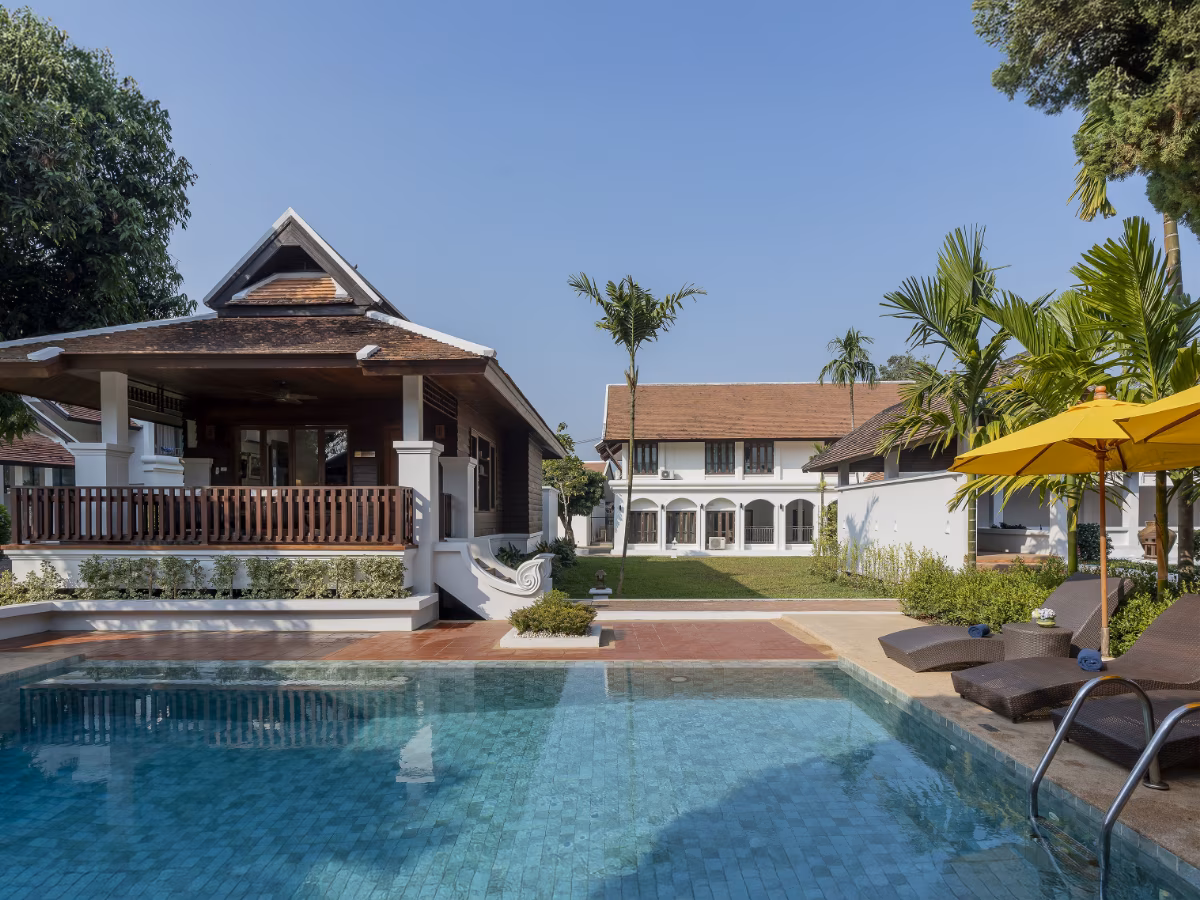Swimming pool and yellow umbrella in front of Thai-style villas and lawn at The Dawn Wellness Centre