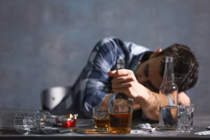 man-slumped-over-table-with-alcohol