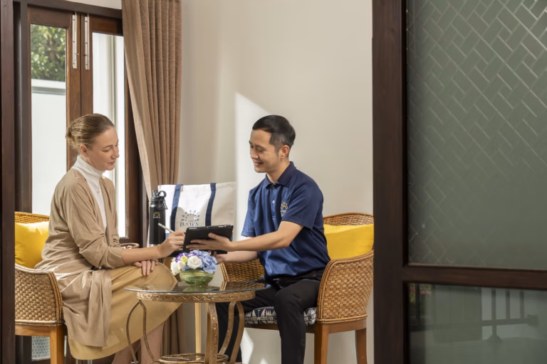A staff member holds a tablet while a woman signs it with a stylus during a welcome consultation at The Dawn.