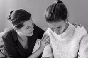 Black and white photo of an older woman comforting a sad young woman on a sofa