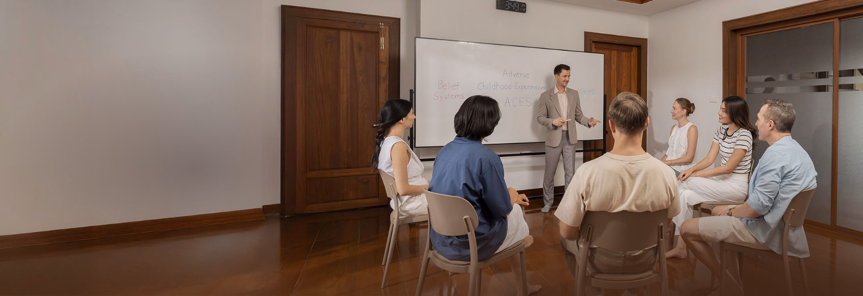 Group therapy session at The Dawn depression retreat in Thailand, with a therapist presenting on adverse childhood experiences to seated clients